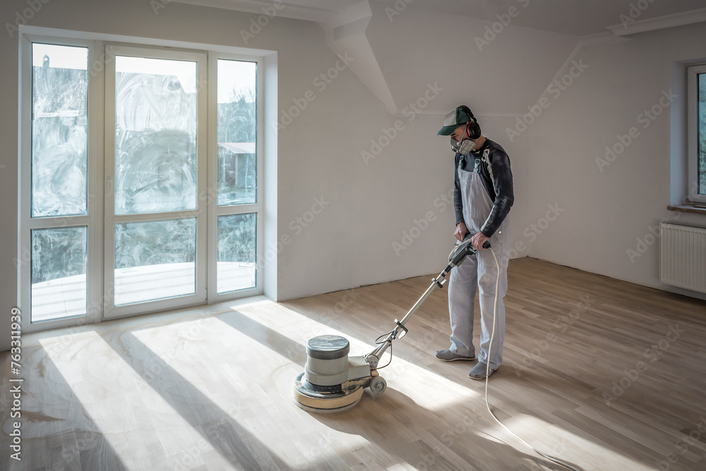 Fototapeta premium Professional worker polishing sanding parquet floor with orbital polishing machine