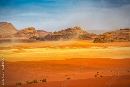 The wind raises the dust in sunny Sahara, Wadi Rum or Arabian desert
