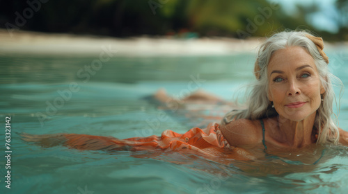 Portrait of a beautiful mature woman swimming at tropical beach.