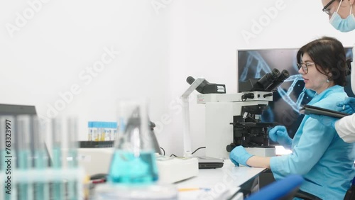 Medical science laboratory with diverse team of professional biotechnology scientists developing drugs, female biochemist working on computer demonstrating gene therapy interface. photo