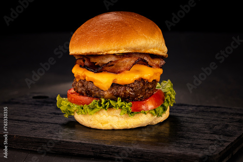 Hamburger accompanied by fries and soda in a studio photo with brown and black wood photo