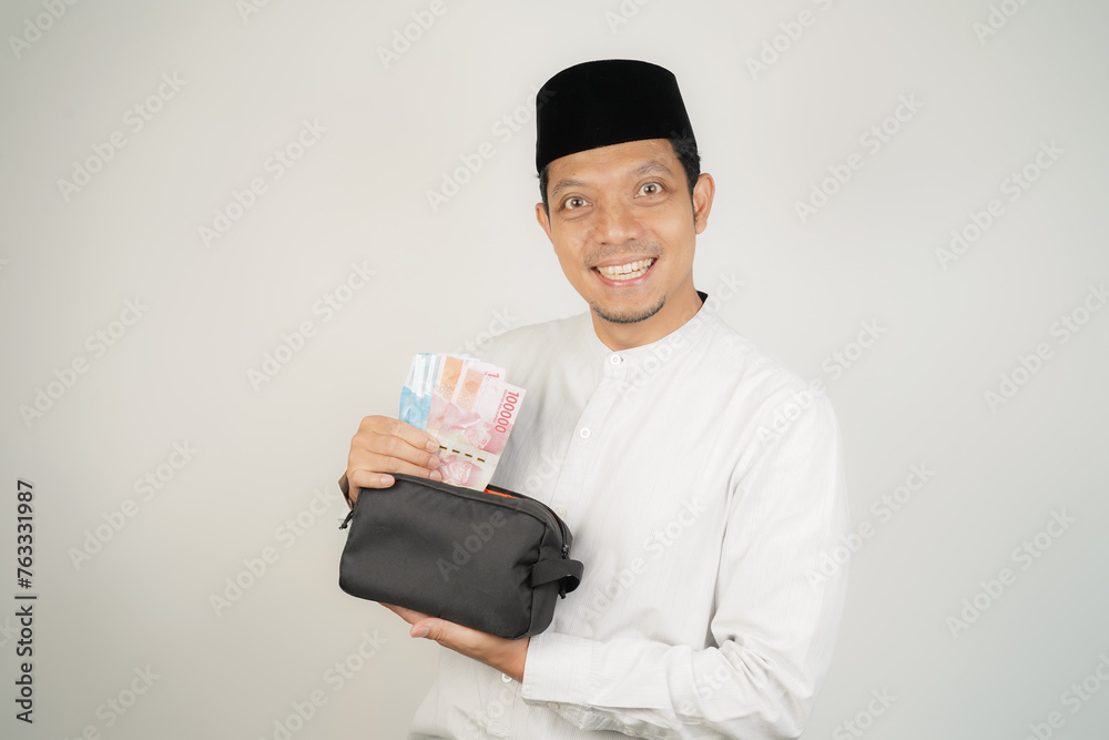 happy asian muslim man holding money, wearing arabic costume on isolated background happy asian muslim man holding money, wearing arabic costume on isolated background