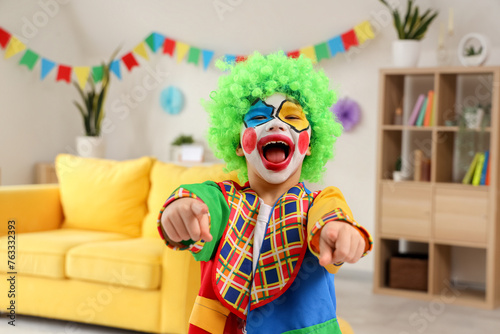 Funny little boy in clown costume pointing at viewer  closeup. April Fools  Day celebration