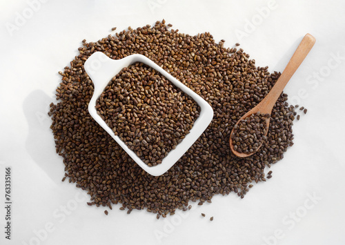 Cassia seeds with bowl and spoon. Isolated on white background. Top view. 
 photo