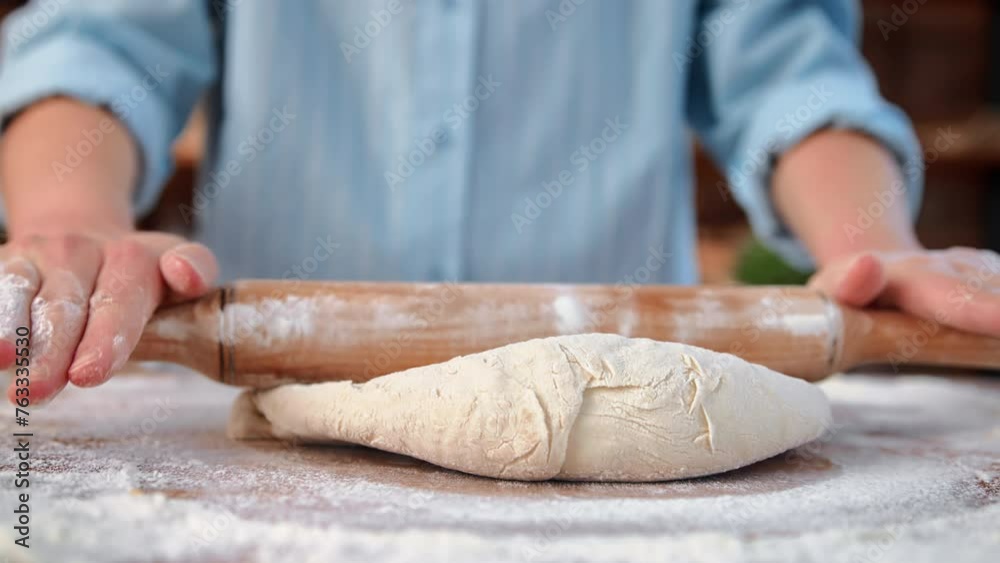 Housewife rolling out dough for bread or pizza in homemade bakery kitchen, closeup of female hands Housewife rolling out dough for bread or pizza in homemade bakery kitchen, closeup of female hands