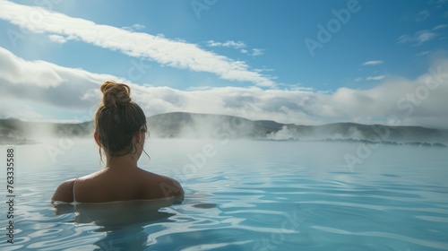 Woman relaxing in a hot spring with a serene mountain view, ideal for wellness, travel, and leisure themes.
