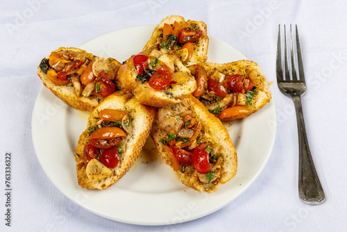 Italian bruschetta, bread with olive oil and tomatoo, g on a white plate on a white tablecloth. photo