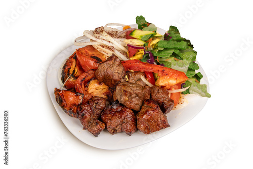 A plate of spicy beef tikka or beek skewer chunks with grilled vegetables and green salad isolated on white photo