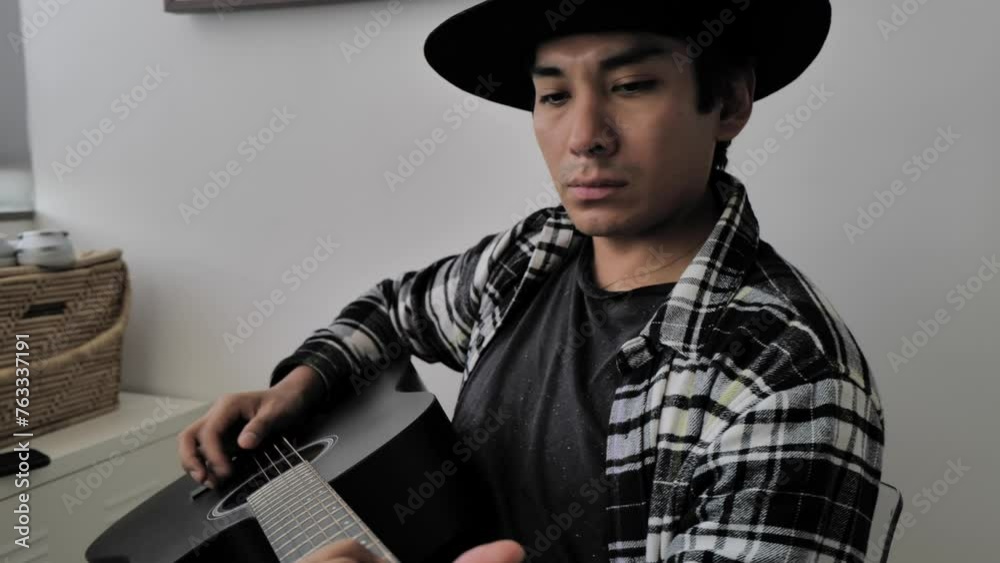Latin man playing acoustic guitar at home