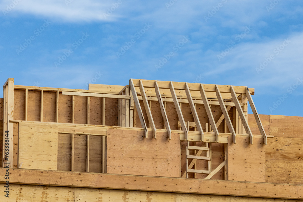 Fototapeta premium Rafters and plywood sheathing on the walls of a multi unit wood residential construction project with a lot of interesting detail 