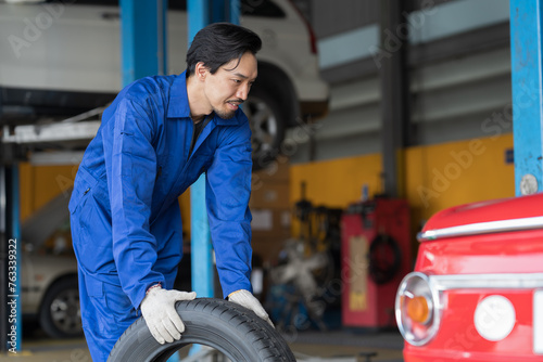 Male mechanic working at garage. Professional Asian male mechanics checks, repair and maintenance tires car at auto car repair service. Car service and Maintenance concept