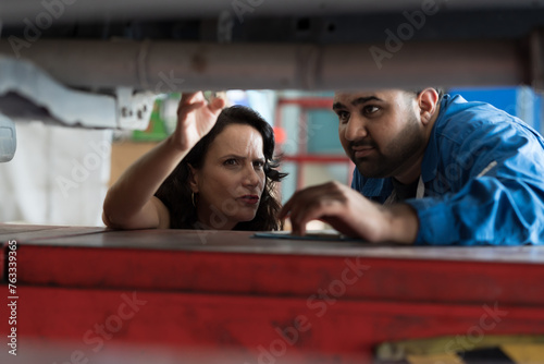 Group of male mechanic working at garage. Male mechanics and woman customer discussing together at auto car repair service. Car service and Maintenance concept