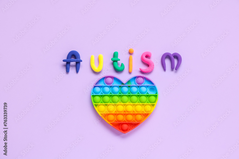 Word AUTISM with colorful pop it on lilac background