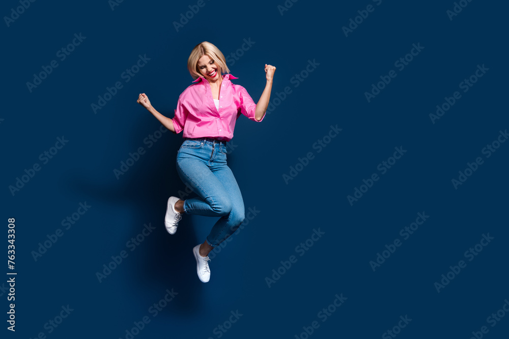 Full size photo of pretty young girl jump celebrate champion winning wear trendy pink outfit isolated on dark blue color background