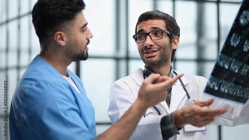 Doctors and an intern examine an X-ray of a patient. MRI scans of brain activity and scientists. Doctors and an intern examine an X-ray of a patient. MRI scans of brain activity and scientists.