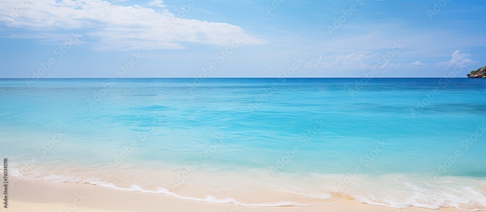 Blue ocean view with sandy beach and distant rock