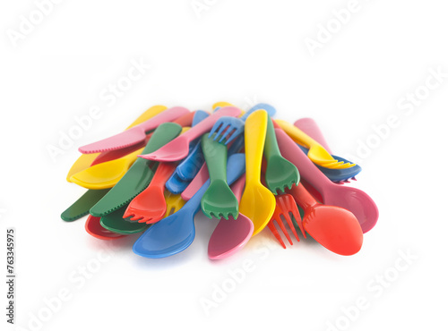 Pile of plastic bright colours cutlery forks knives spoons isolated on white background. Concept of reusable party and tableware, kids parties lunch dinner, sustainable living, nursery school children