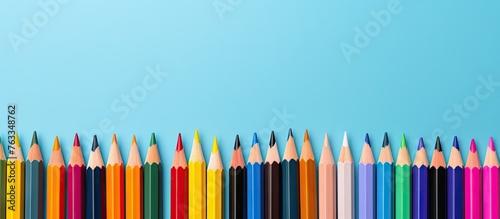 A row of vibrant colored pencils on a blue surface