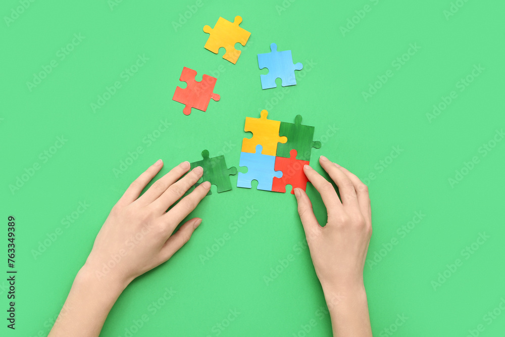 Female hands doing puzzle on green background. Concept of autistic disorder Female hands doing puzzle on green background. Concept of autistic disorder