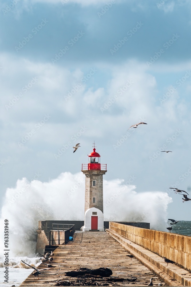 Storm waves over lighthouse, Portugal - sky enhanced. Windy coast. Bad weather with waves crashing in Porto harbor.