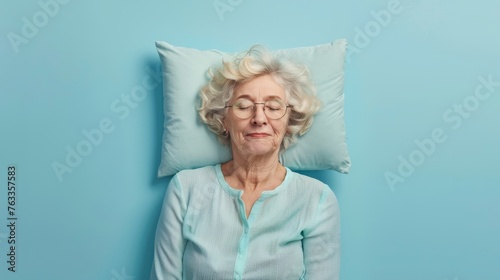 Elderly woman sleeping on pillow isolated on pastel blue colored background Sleep deeply peacefully rest. Top above high angle view photo portrait of satisfied .senior wear blue shirt