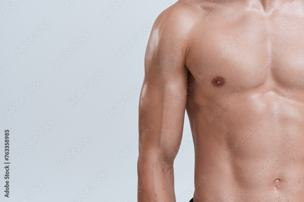cropped view of athletic man posing topless on gray background and playing his muscles on camera cropped view of athletic man posing topless on gray background and playing his muscles on camera