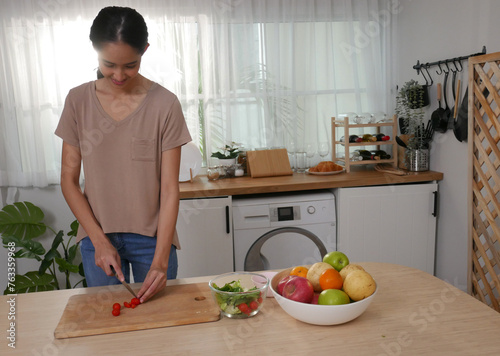 Young woman is cooking vegetable salad in the kitchen, holiday activity