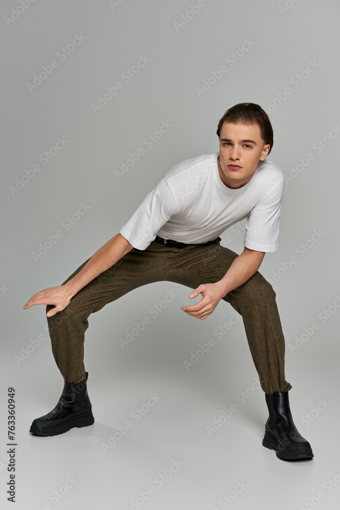 appealing sophisticated man in elegant attire with brown pants posing and looking at camera appealing sophisticated man in elegant attire with brown pants posing and looking at camera
