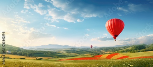A red hot air balloon soaring above a green landscape with distant mountains