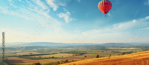 Hot air balloon soaring above a rural farmland