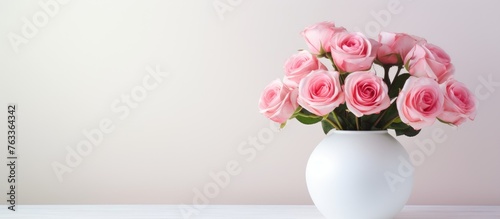 White vase with pink roses on table