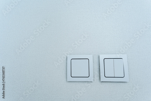 Two rectangular electric blue switches with a brand logo on a white ceiling