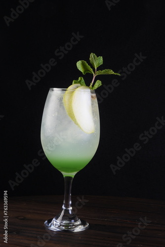 refreshing alcoholic drink with berries, ice vodka and gin, lemon peel served in glass cup on the counter on blurred background