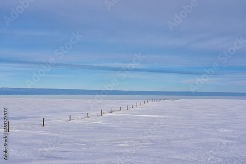 Wintery landscape in rural Saskatchewan with a fence leading off into the distance; Assiniboia, Saskatchewan, Canada