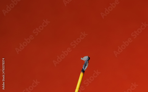 A closeup of a stick of an finished incense stick on the red background for graphic and web design use