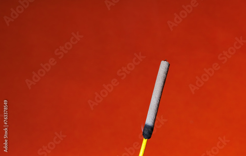 A closeup of a finished incense stick on the red background for graphic and web design use photo