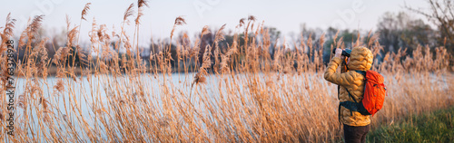 Bird watching at lake. Ornithologist with binoculars observe wildlife avian animals in natural habitat. Panoramic view photo