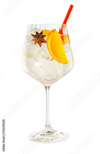Crystal balloon glass of vodka tonic garnished with star anise and orange isolated on white background.