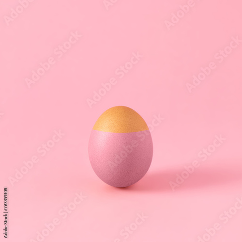 Colored Easter egg with holy head against pastel pink background. Minimal aesthetic Christian holiday composition.
