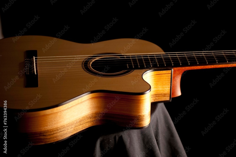 Obraz premium Classical Spanish flamenco guitar close up, dramatically lit isolated on black background with copy space.