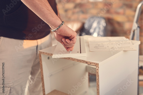 Man working and assembling furniture in a new apartment.