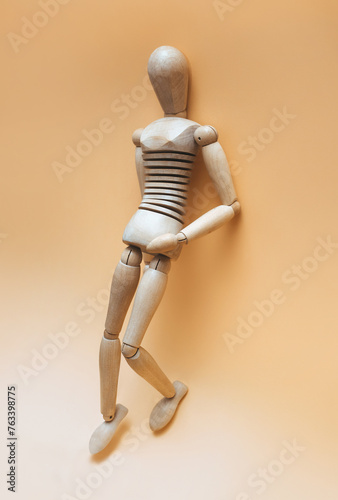 A wooden mannequin (female or male) stands with one leg raised in a waiting position. The concept of prostitution, gigolo, selling love and sexual paid services.