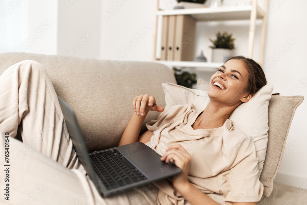 Smiling woman working on laptop at home: A modern domestic freelance job Smiling woman working on laptop at home: A modern domestic freelance job