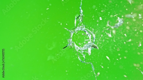 Close-up of gunshot through the glass, shattering against the green background © Lukas Gojda