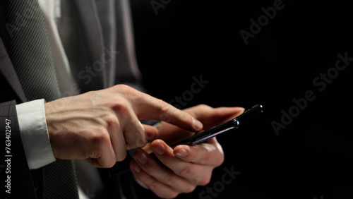 A businessman works with a close-up phone in a dark office