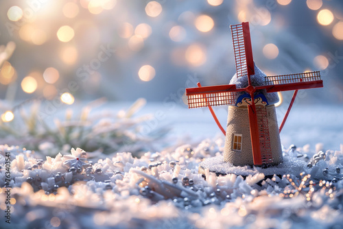 A miniature, festive windmill nestled in a snowy landscape, with softly blurred background lights creating a dreamy atmosphere.