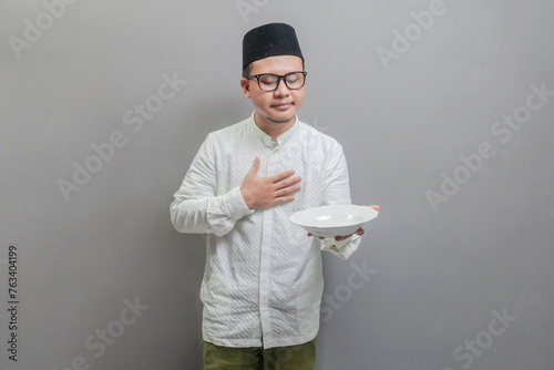 Asian Muslim man holding a plate while waiting for the time photo