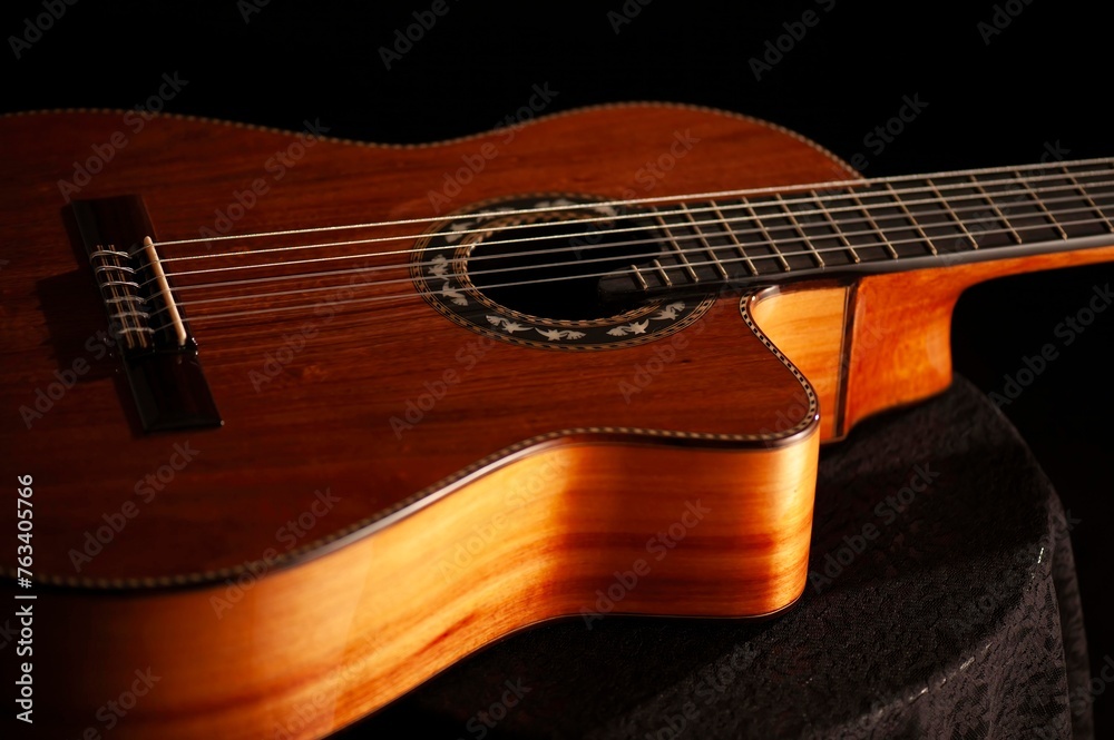 Fototapeta premium Classical Spanish flamenco guitar close up, dramatically lit isolated on black background with copy space.