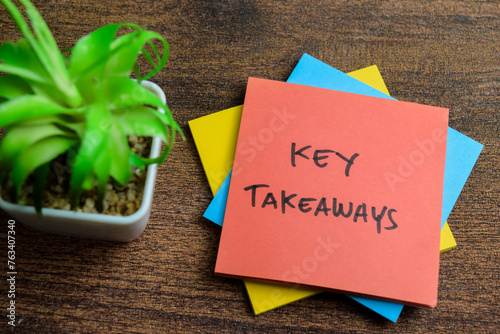 Concept of Key Takeaways write on sticky notes isolated on Wooden Table.