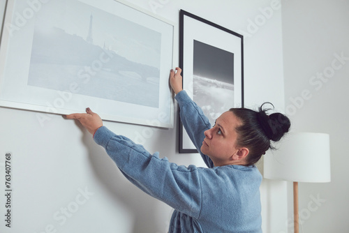 Woman hanging pictures on the wall and cleaning, remodeling apar photo